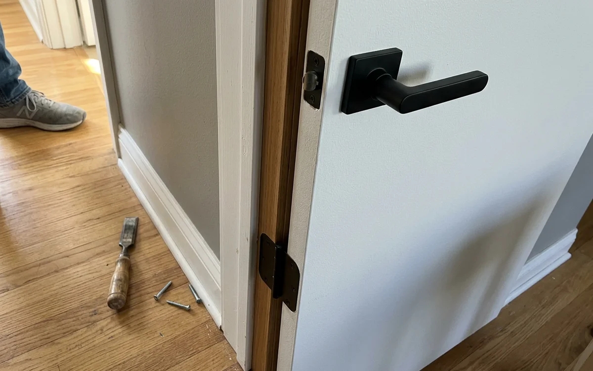 Solid-core interior door edge and hinge detail with a matte black lever handle